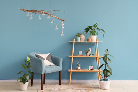 Comfortable armchair, shelving unit and houseplant near blue wallの写真素材
