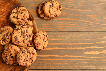Plate of tasty cookies with chocolate chips on wooden backgroundの写真素材
