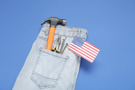 Hammer, pliers and USA flag in jeans pocket on blue background. labor day celebrationの写真素材