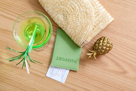 Glass of cocktail, passport, ticket and female bag on wooden tableの写真素材