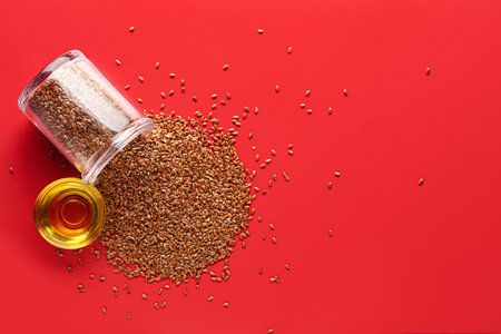 Glass bowl of flax oil and jar with seeds on red backgroundの写真素材
