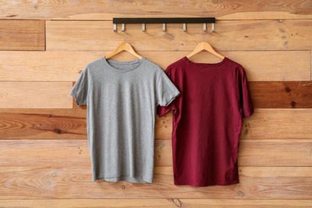 Stylish t-shirts hanging on wooden backgroundの写真素材