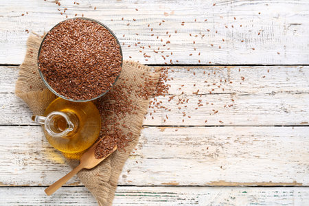 Decanter of flax oil and bowl with seeds on white wooden backgroundの写真素材