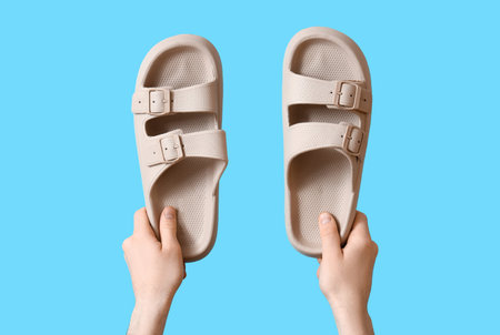 Male hands with summer sandals on blue background