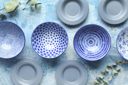 Set of different plates and eucalyptus branches on light blue table