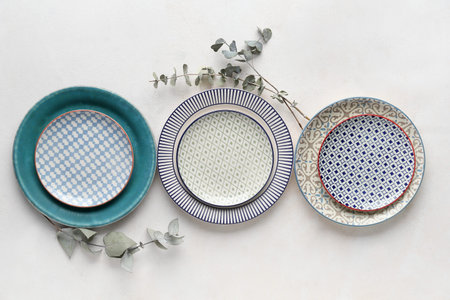 Different clean plates and eucalyptus branches on gray table