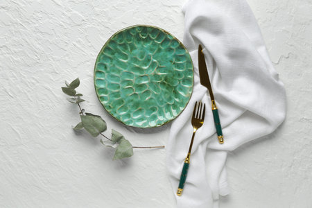 Table setting with clean plate, cutlery and eucalyptus branch on gray backgroundの写真素材