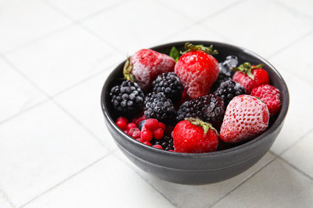 Bowl of frozen berries on white tile backgroundの写真素材