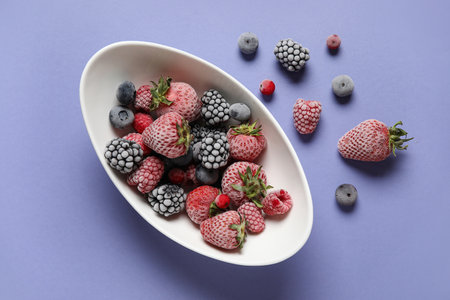 Bowl of frozen berries on purple backgroundの写真素材