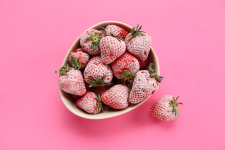 Bowl of frozen strawberries on pink backgroundの写真素材