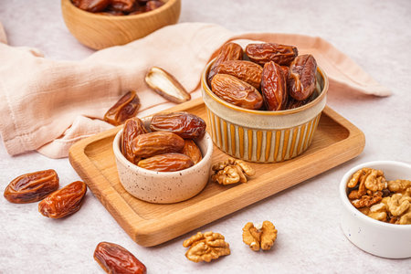 Bowls with dried dates on light background