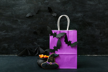 Composition with shopping bag, bats, tasty cookies and candy corns for Halloween on dark backgroundの写真素材