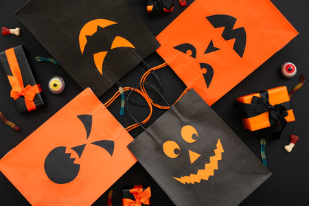 Composition with different shopping bags and tasty candies for Halloween on dark backgroundの写真素材