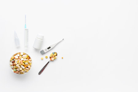 Pills, digital thermometer and syringe on white backgroundの写真素材