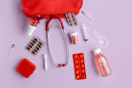 Composition with first aid kit, stethoscope, pills and medical supplies on lilac backgroundの写真素材