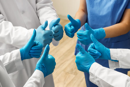 Doctors in medical gloves showing thumbs-up at clinic, closeupの写真素材