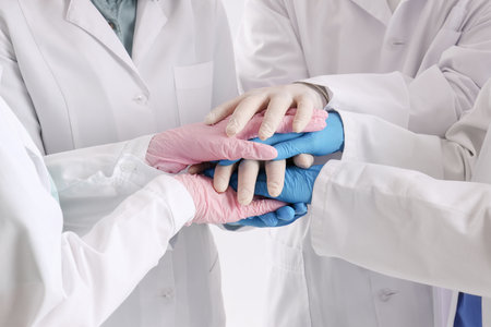 Doctors in medical gloves putting hands together at clinic, closeupの写真素材