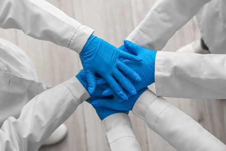 Doctors in medical gloves putting hands together at clinic, top viewの写真素材