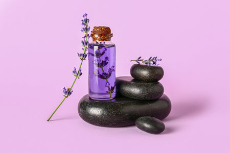 Composition with bottle of lavender essential oil and spa stones on color backgroundの写真素材