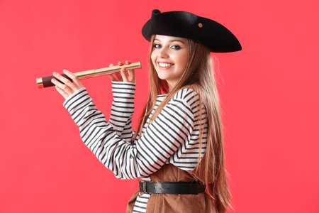 Beautiful female pirate with spyglass on red backgroundの写真素材