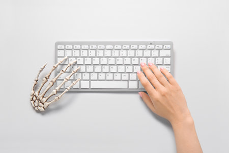 Female and skeleton hands with modern computer keyboard on white background. halloween celebrationの写真素材