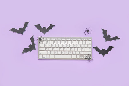 Composition with modern computer keyboard, spiders and paper bats for Halloween on purple backgroundの写真素材