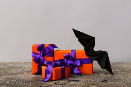 Beautiful gift boxes and bat for Halloween on gray grunge tableの写真素材
