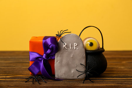 Beautiful gift box, tasty cookie and spiders for Halloween on wooden table, closeupの写真素材