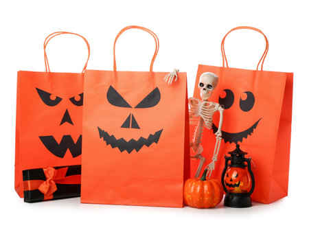 Orange shopping bags, skeleton, lantern and gift box for Halloween on white backgroundの写真素材