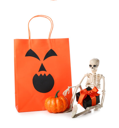 Orange shopping bag, skeleton, gift box and pumpkin for Halloween on white backgroundの写真素材