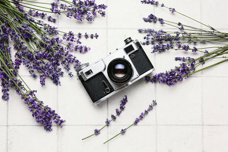 Beautiful lavender flowers and photo camera on light tile backgroundの写真素材