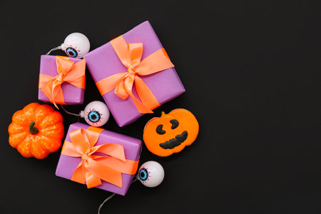 Composition with gift boxes and tasty candies for Halloween on dark backgroundの写真素材