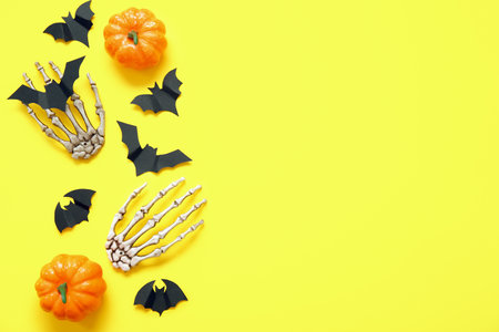 Composition with pumpkins, paper bats and skeleton hands on yellow background. halloween celebration conceptの写真素材