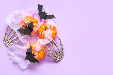 Composition with pumpkins, web, skeleton hands and paper bats on purple background, closeup. halloween celebration conceptの写真素材