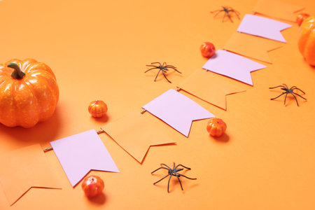 Garland made of paper flags, pumpkins and spiders for Halloween celebration on orange background, closeupの写真素材