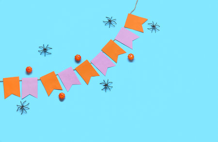 Garland made of paper flags, pumpkins and spiders for Halloween celebration on blue backgroundの写真素材