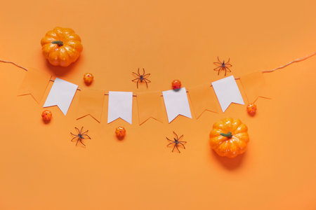 Garland made of paper flags, pumpkins and spiders for Halloween celebration on orange backgroundの写真素材