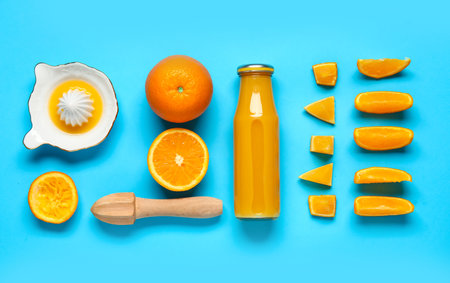 Bottle of fresh orange juice and juicers on blue backgroundの写真素材