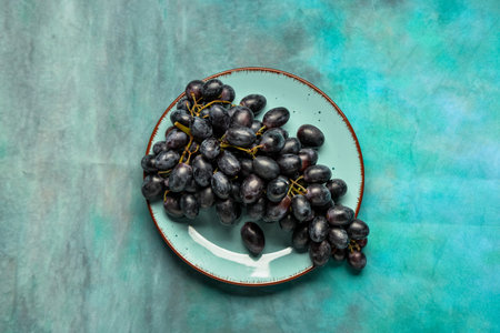 Plate with sweet black grapes on blue backgroundの写真素材