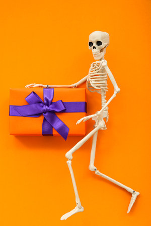 Composition with skeleton and gift box for Halloween on orange backgroundの写真素材
