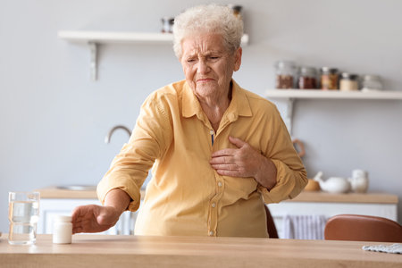 Elderly woman with heart attack going to take medicine at homeの写真素材