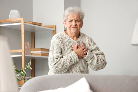 Senior woman having heart attack at homeの写真素材