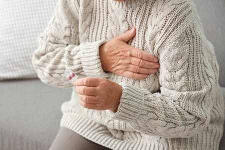 Elderly woman with pills having heart attack at homeの写真素材