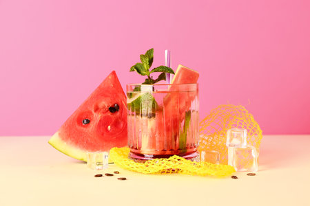 Glass of fresh watermelon lemonade with lime and mint on yellow tableの写真素材