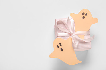Beautiful gift box and ghosts made of paper for Halloween on white backgroundの写真素材