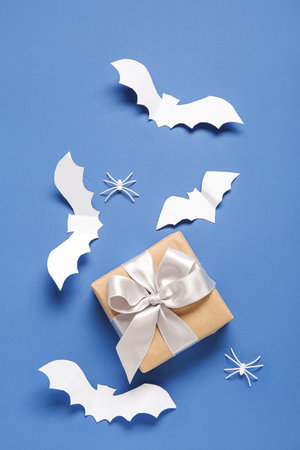 Composition with beautiful gift box, spiders and bats made of paper for Halloween on blue backgroundの写真素材