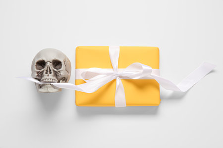 Composition with beautiful gift box and skull for Halloween on white backgroundの写真素材