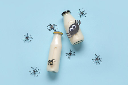 Bottles of milk and spiders for Halloween on blue backgroundの写真素材