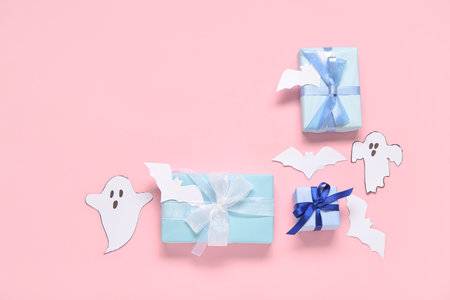 Composition with beautiful gift boxes, ghosts and bats made of paper for Halloween on pink backgroundの写真素材