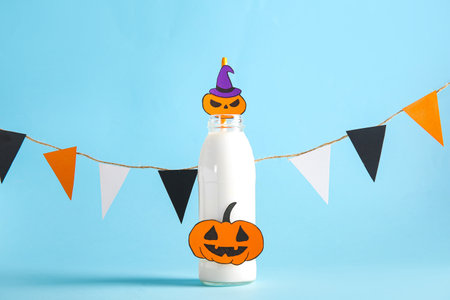 Bottle of milk, flags and pumpkins made of paper for Halloween on blue backgroundの写真素材